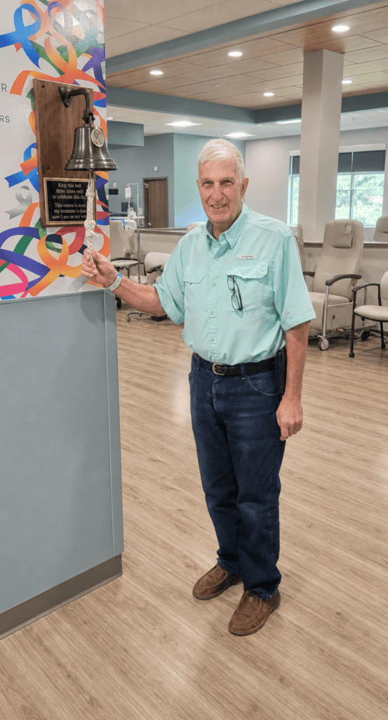 A man, having just completed his last chemo treatment, is ringing the victory bell.